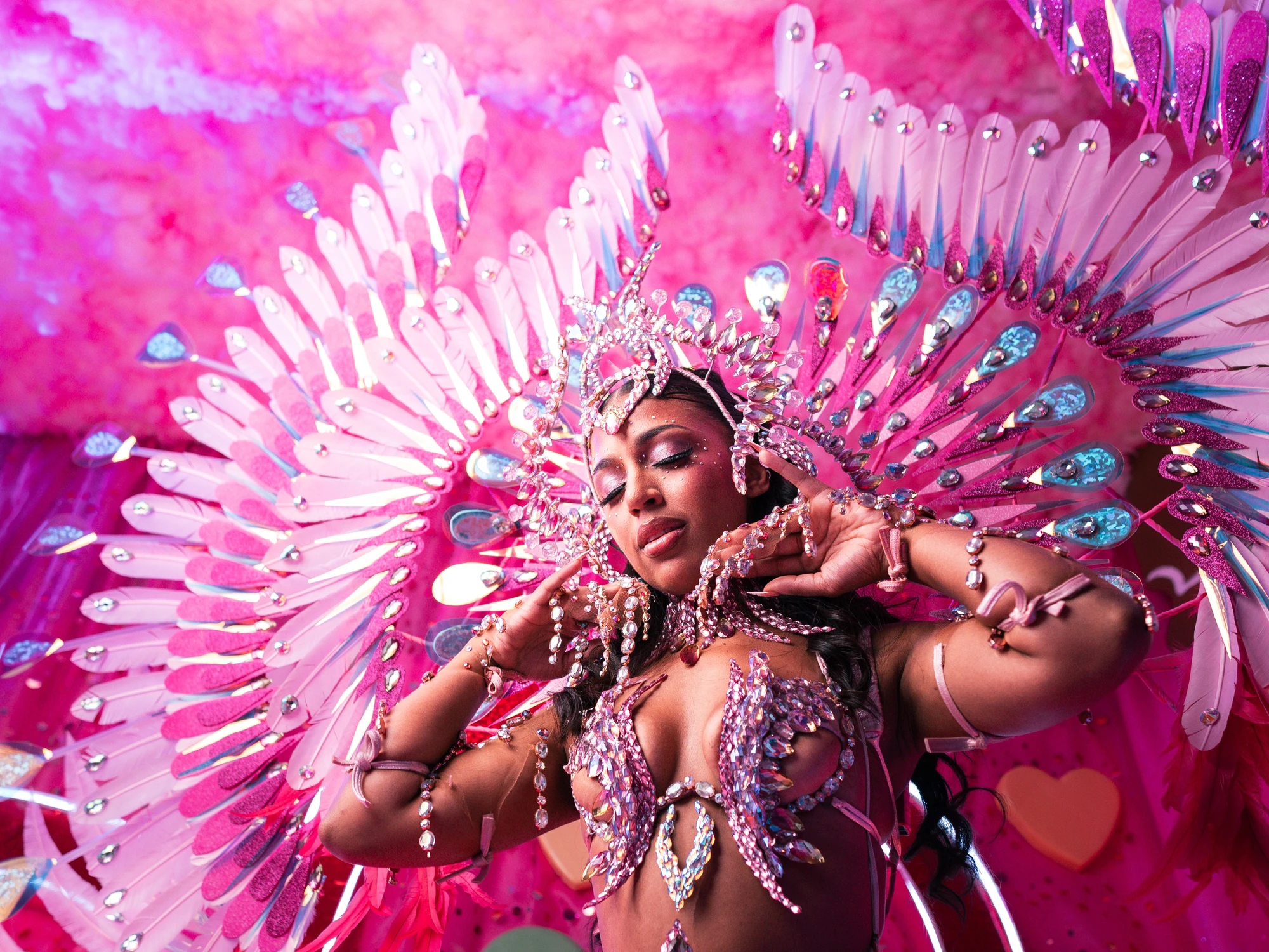 The BLUSH costume shown in full — jewelled bra, belt and leg chains beneath a feathered backpack at full span.