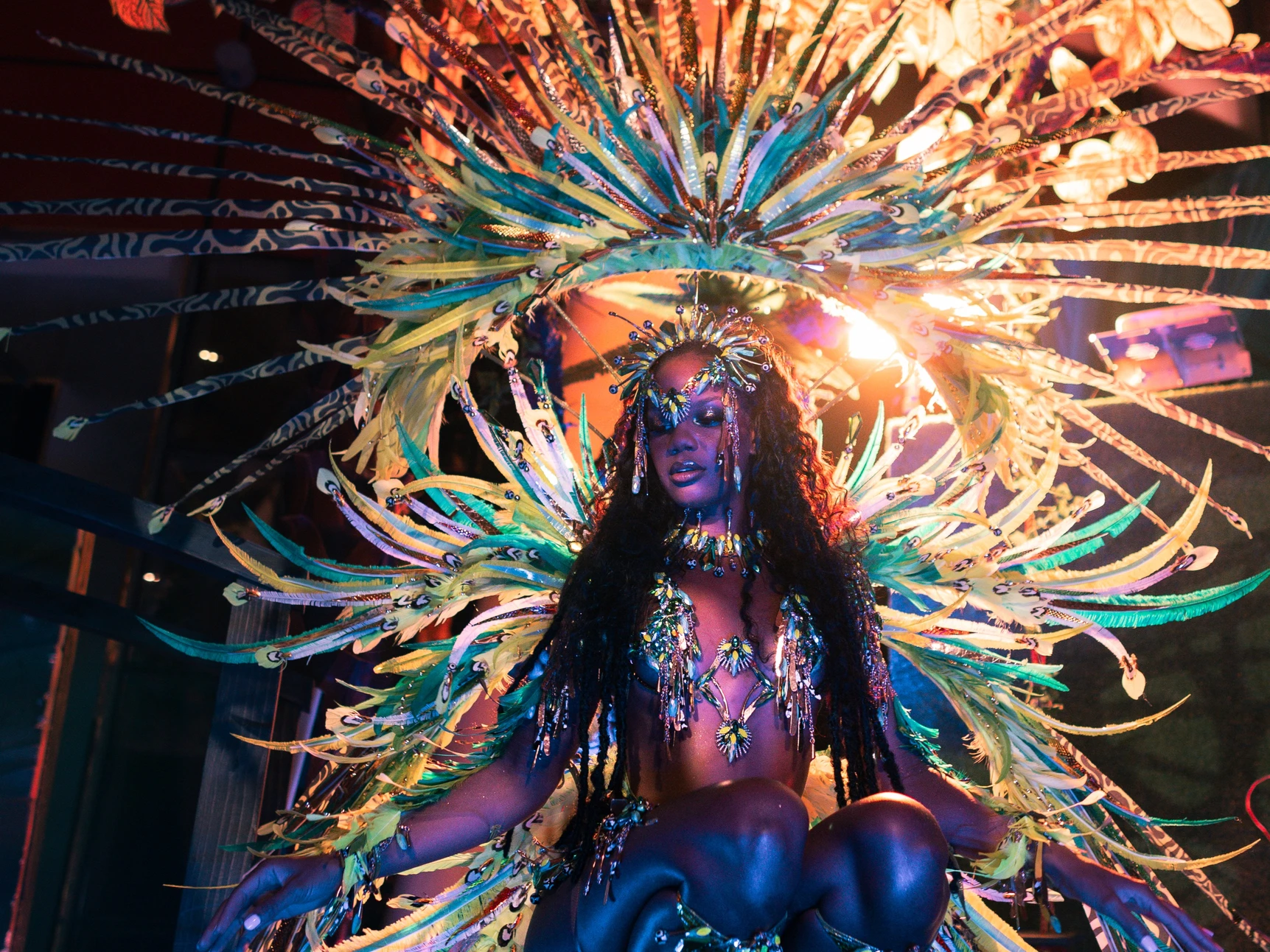 The IVY costume shown in full — jewelled bra, belt and leg chains beneath a feathered backpack at full span.