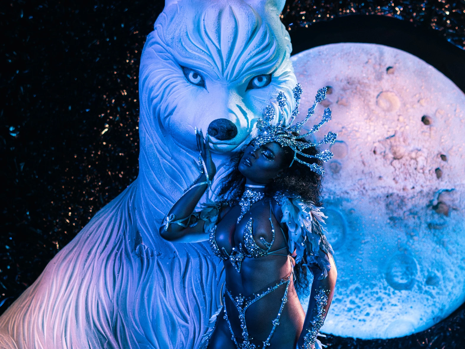 The LUNA costume shown in full — jewelled bra, belt and leg chains beneath a feathered backpack at full span.