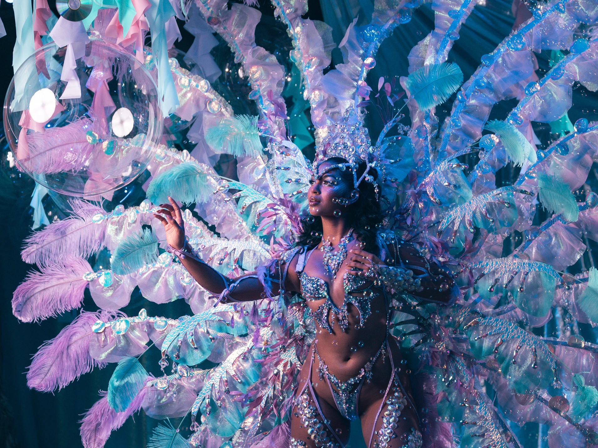 The MIST costume shown in full — jewelled bra, belt and leg chains beneath a feathered backpack at full span.