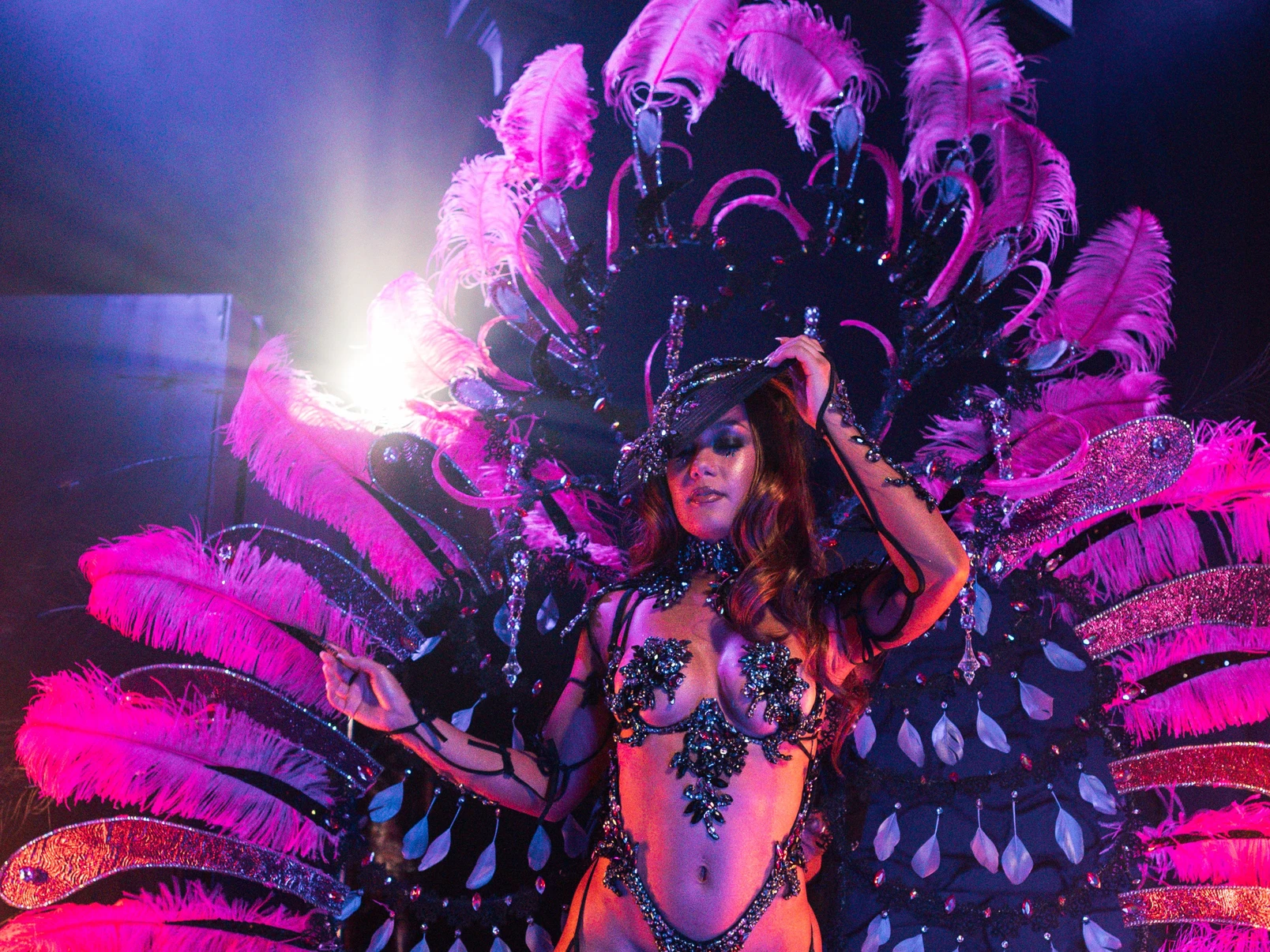 The NOIR costume shown in full — jewelled bra, belt and leg chains beneath a feathered backpack at full span.