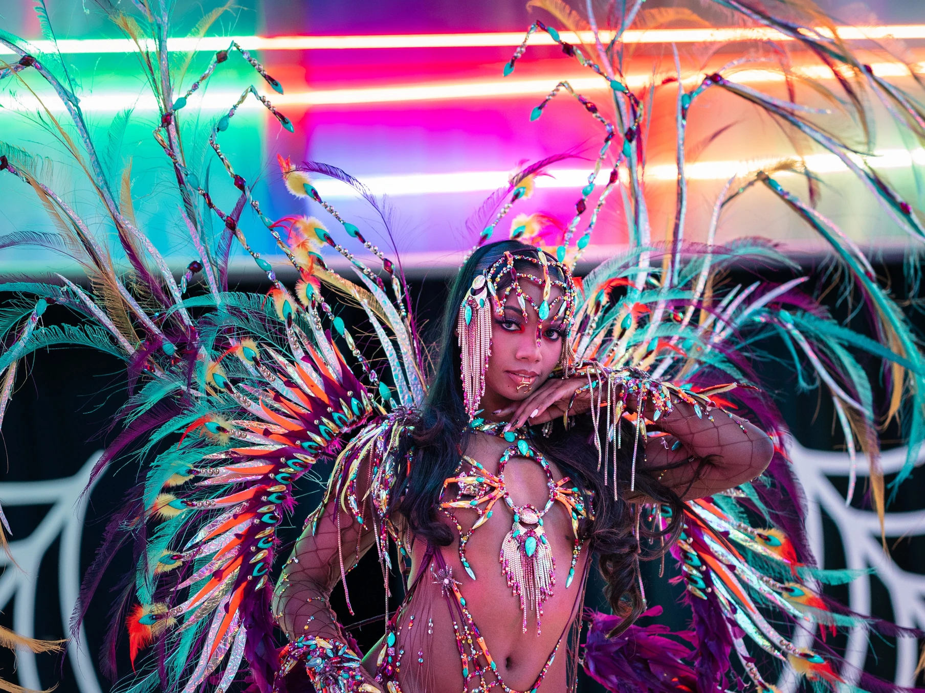The RUSE costume shown in full — jewelled bra, belt and leg chains beneath a feathered backpack at full span.